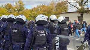 Policjanci zabezpieczają przejście kibiców na stadion.