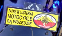 Na zdjęciu znajduje się plakietka z napisem &quot;Patrz w lusterka. Motocykle są wszędzie&quot; Umieszczona jest ona w przedniej części motocyklu.